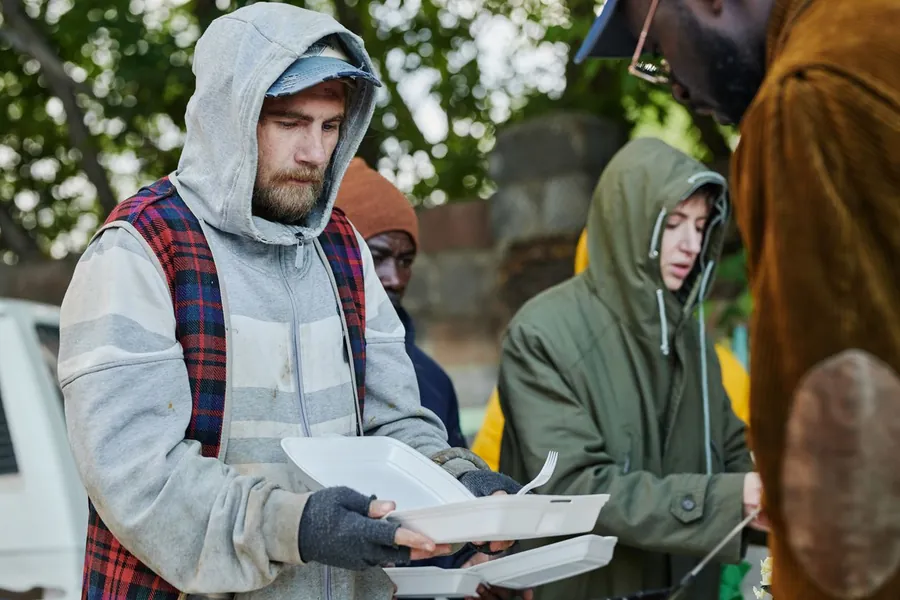 People in hooded jackets receiving takeout meals outdoors