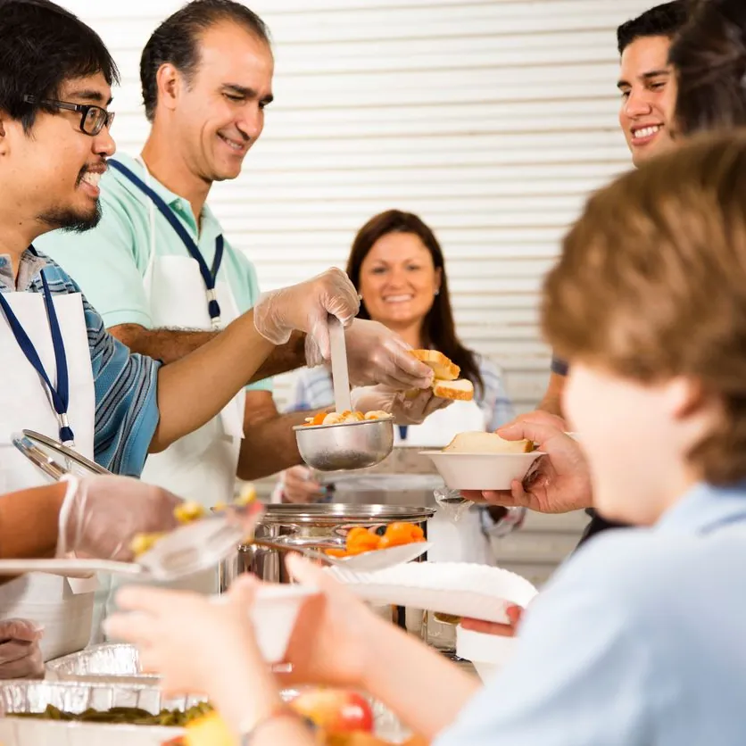 Volunteers serving a hot meal to guests along a buffet line